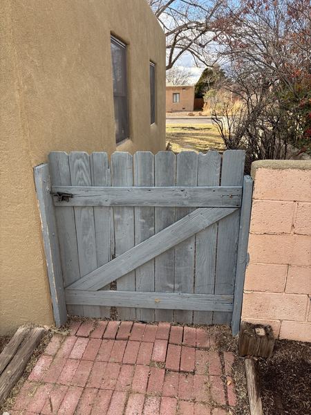Before: weathered wood picket gate between a stucco wall and a block wall