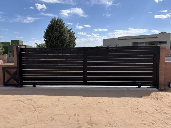 Black horizontal-slat steel sliding gate between block pillars