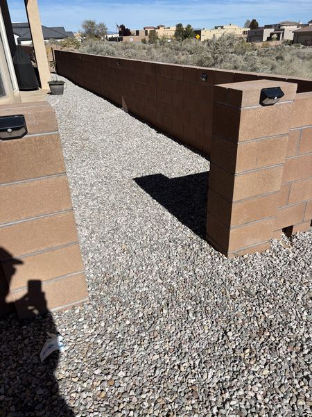 Before: open gap in a block wall beside a gravel path