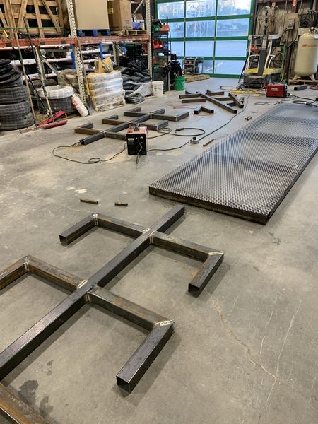 Pipe rack base frames and a mesh deck laid out on the shop floor