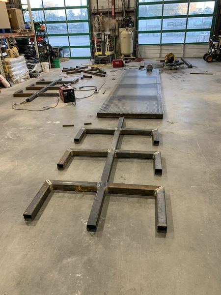 Pipe rack parts laid out in a row on the shop floor