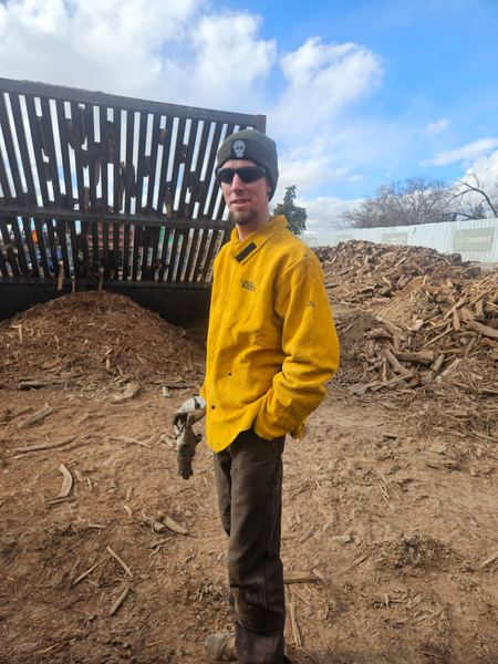 James in a yellow welding jacket, holding welding gloves