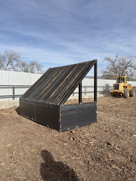 Steel soil separator with a slatted sloped top and plate sides in a dirt yard