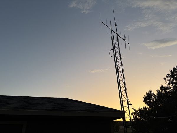 Lattice antenna tower with antennas, silhouetted at sunset