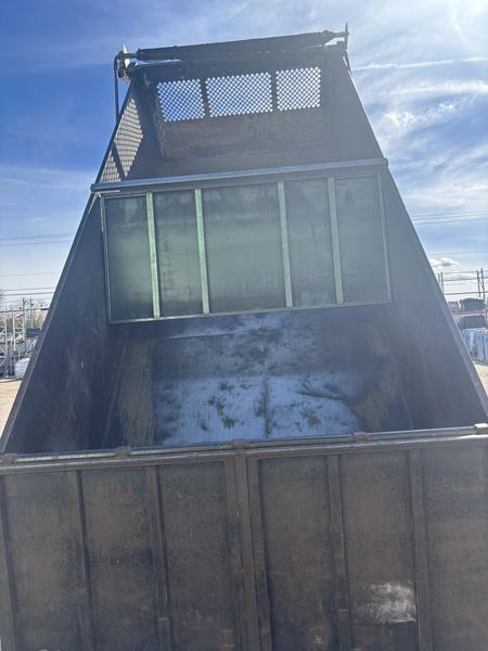 Raised dump truck bed with a mesh-topped divider at the front